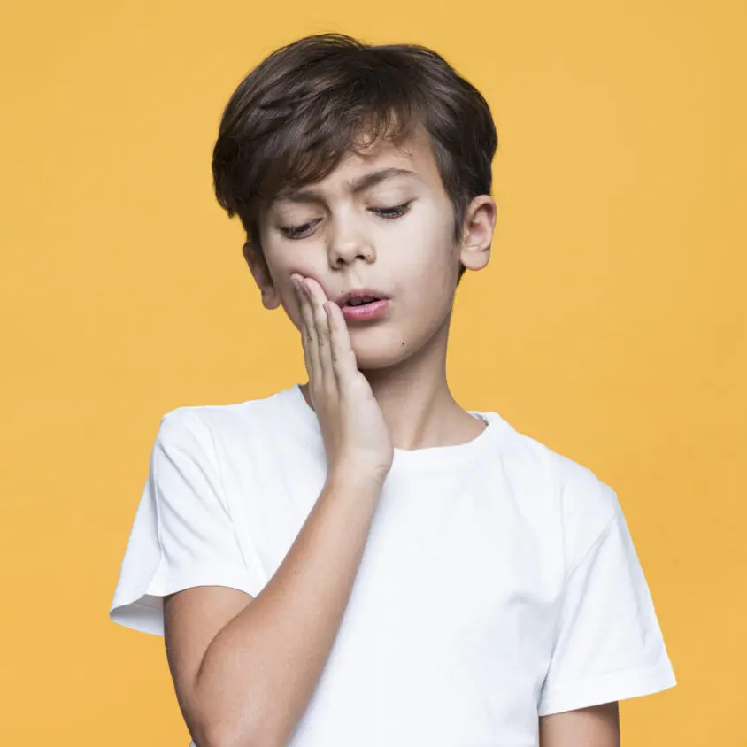 young boy with tooth pain yellow background scaled